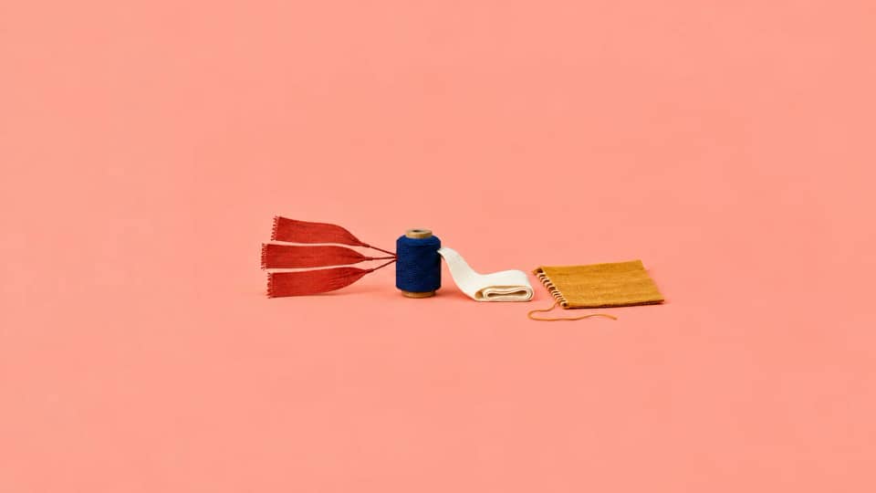 Several incident tabs converge on one bobbin while an output ribbon emerges beside an unfinished engineering cloth.